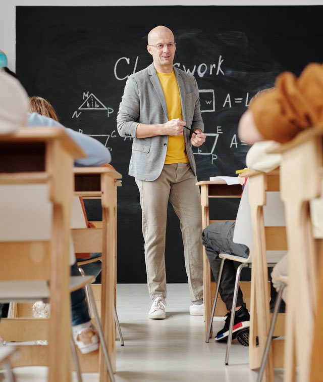 A man in a classroom with some chalk board