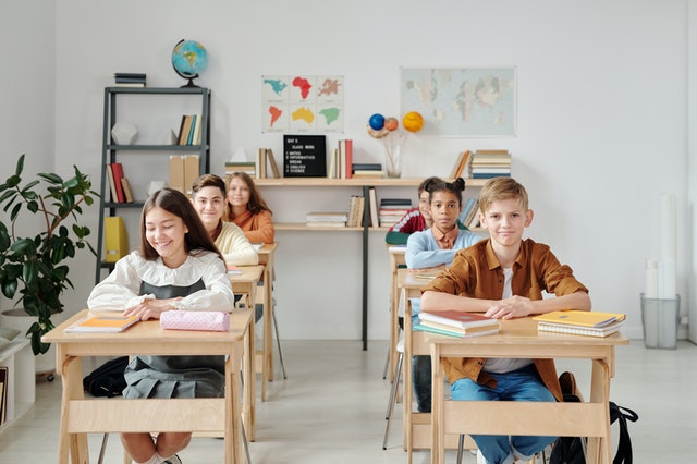 pexels-max-fischer-5211446 (1) A group of children sitting at desks in a classroom.